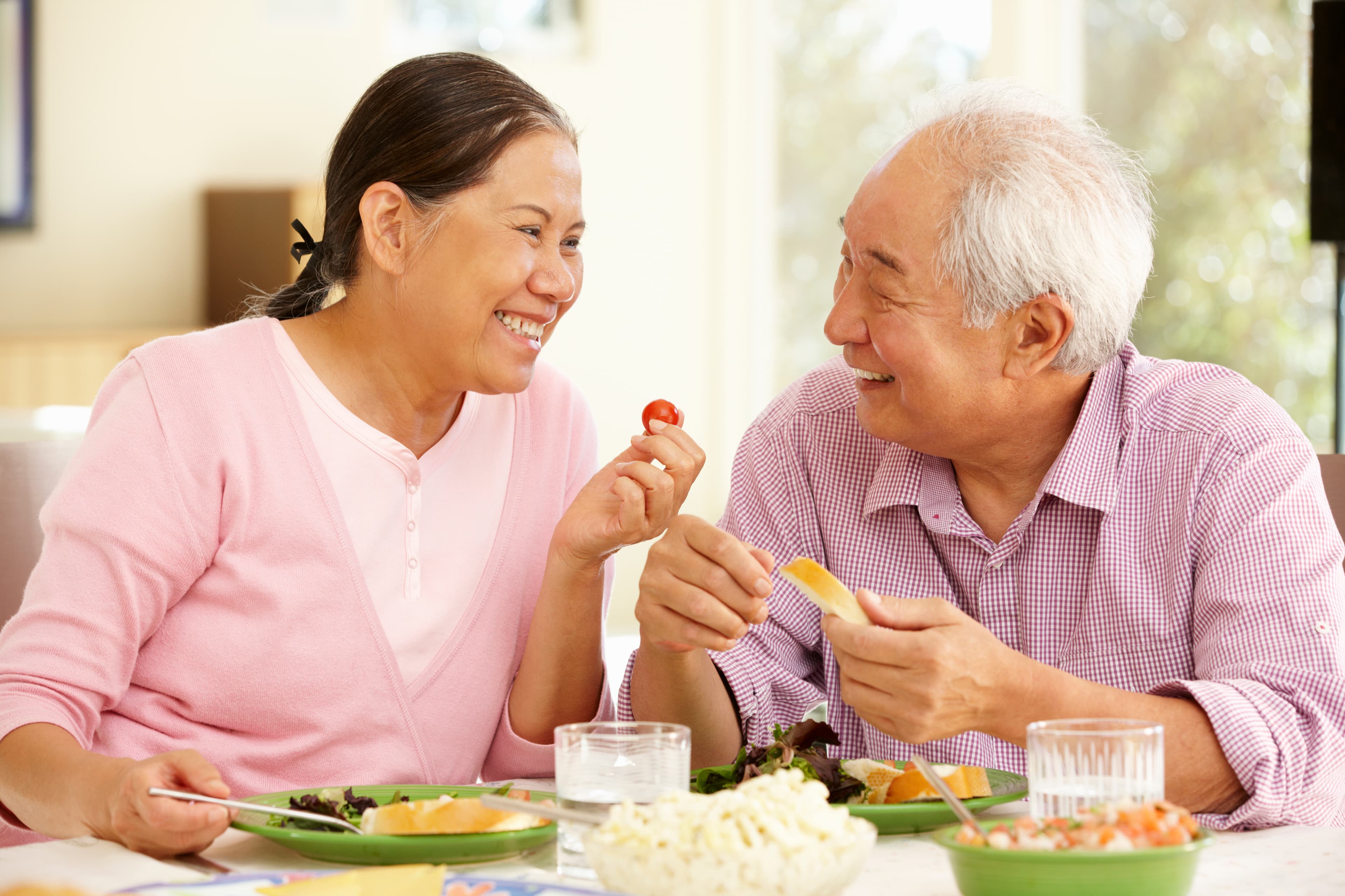 An older couple enjoying a meal together at home, laughing